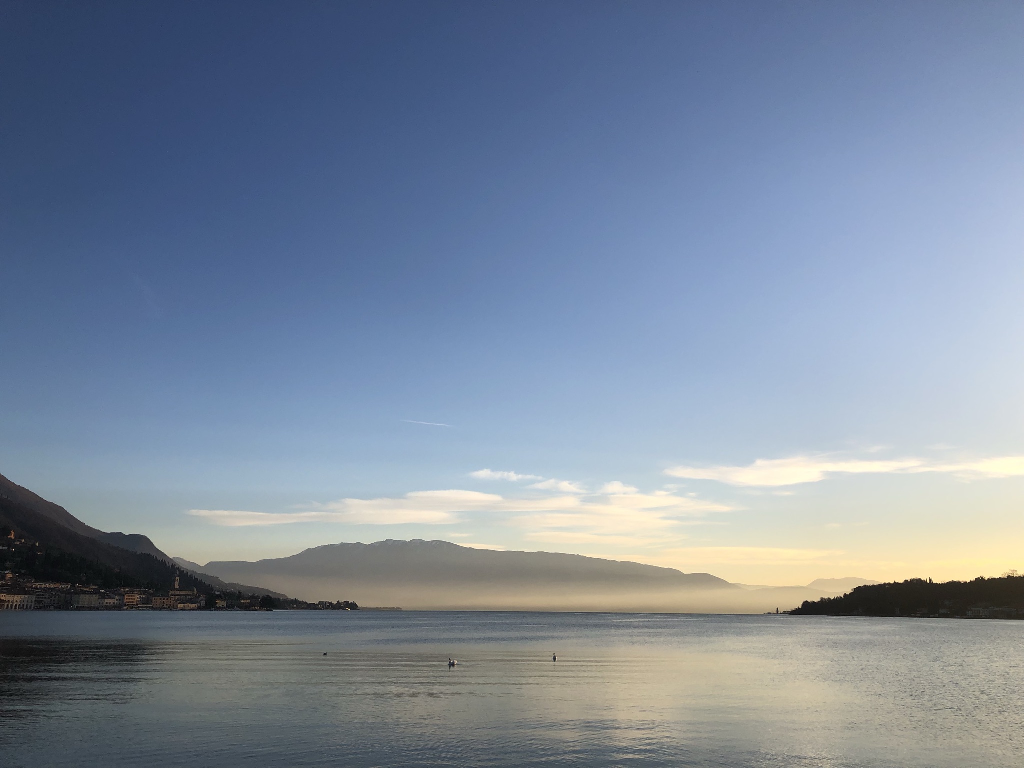 Golden light over Lake Garda, with the waterfront of Salò and mountains beneath a blue sky